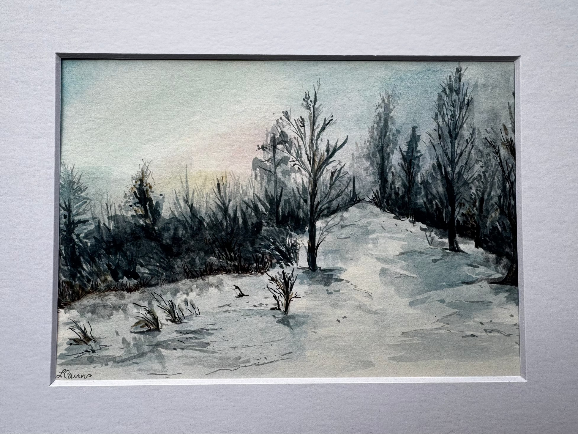 Matted watercolor painting of a winter landscape with trees and a sunset on a light gray background