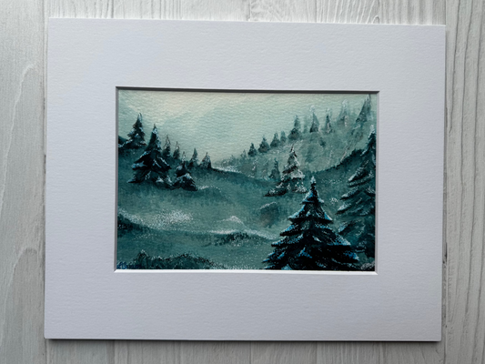 Matted artwork of a forest scene with trees and watercolor textures on a light wooden surface.